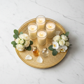Top-down flat lay of luxury Arabic gold tray styled with candles and flowers on marble surface